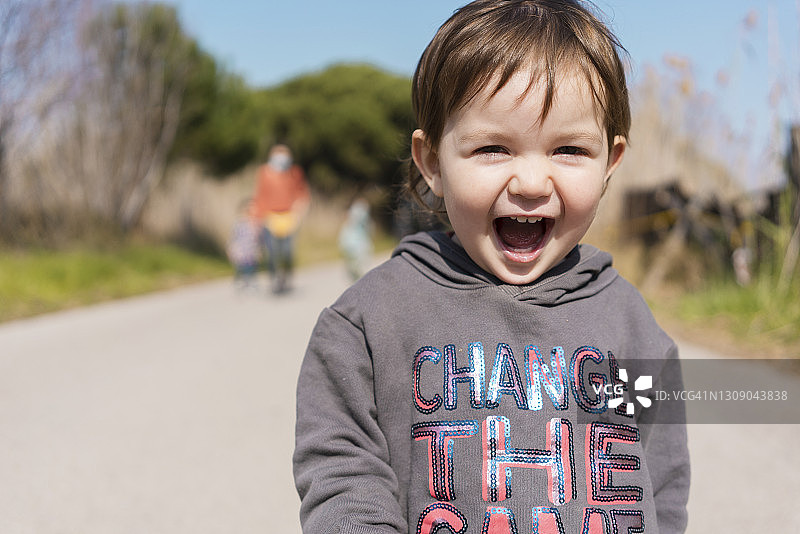 快乐的小女孩在户外奔跑，连帽衫上写着“改变游戏”的信息图片素材