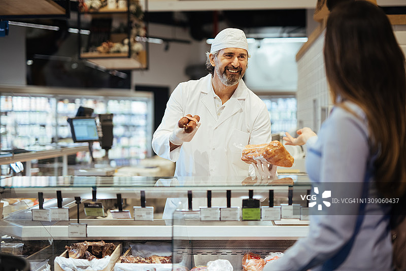 女顾客在超市的熟食柜台选择肉类图片素材