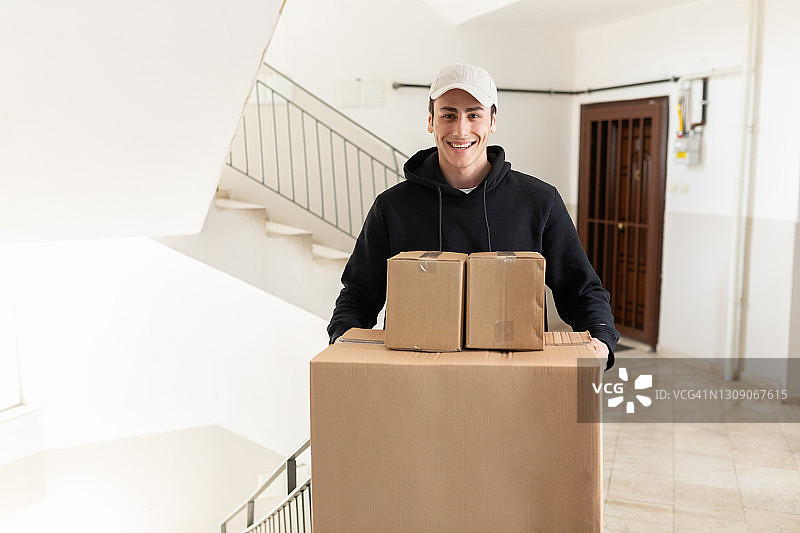 快乐的年轻送货员正在运送纸箱图片素材