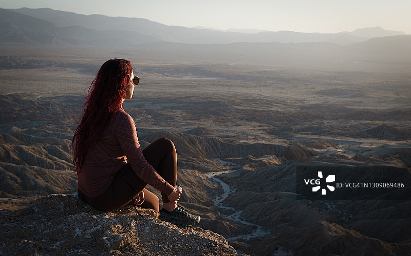 女子坐在山上欣赏荒地山景，美国加利福尼亚州安扎-博雷戈沙漠州立公园图片素材