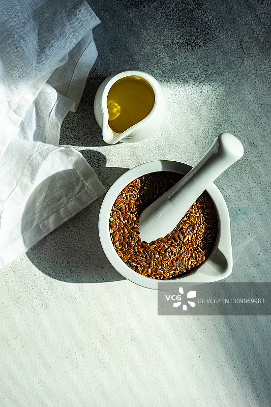 研钵和研杵中的新鲜亚麻籽与一壶橄榄油图片素材