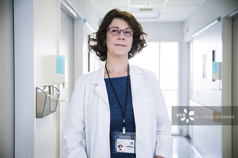 自信的中年医生站在医院走廊里图片素材