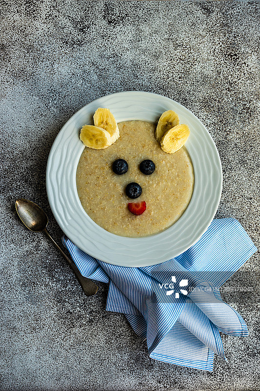 一碗燕麦片，用新鲜水果装饰成熊脸的俯视图图片素材