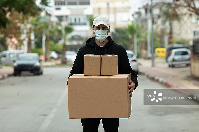 戴防护口罩的快递员运送货物图片素材