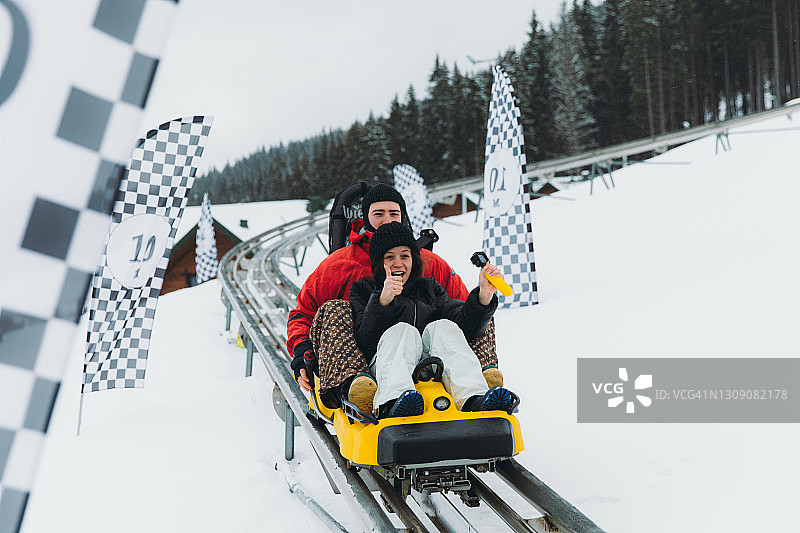 年轻情侣在山区冬季乘坐过山车图片素材