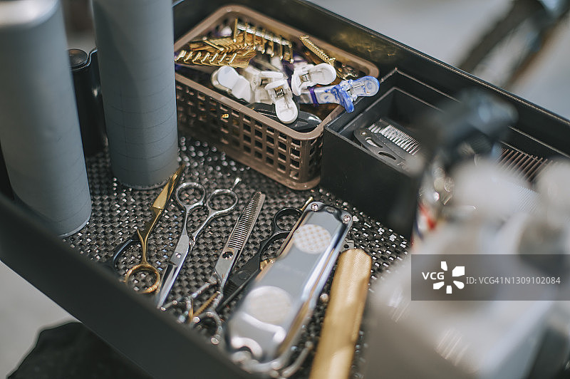 托盘上的理发工具：剪刀、理发器、乳液瓶、梳子、夹子、剃须刀片图片素材