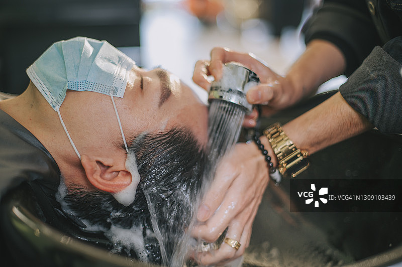 中国男子在理发店享受洗发服务图片素材