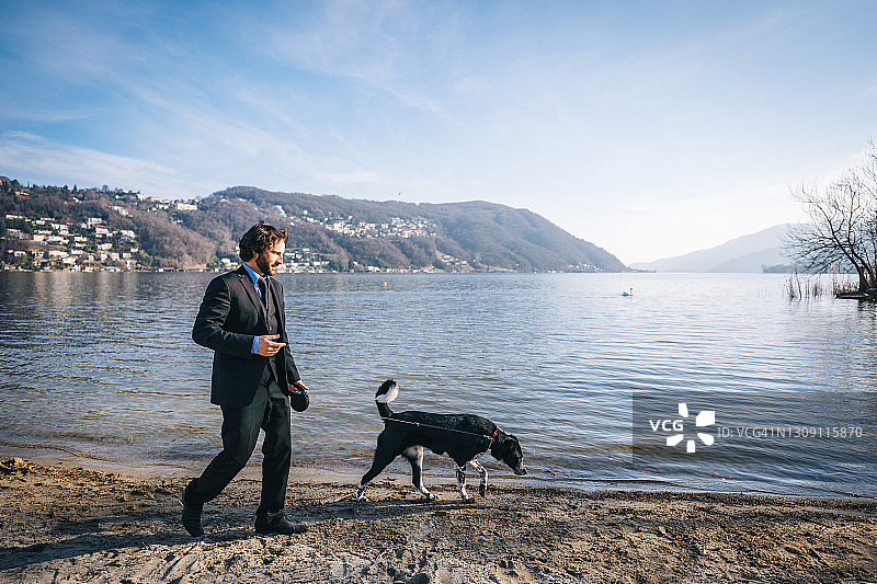 商务人士清晨在湖边遛狗图片素材