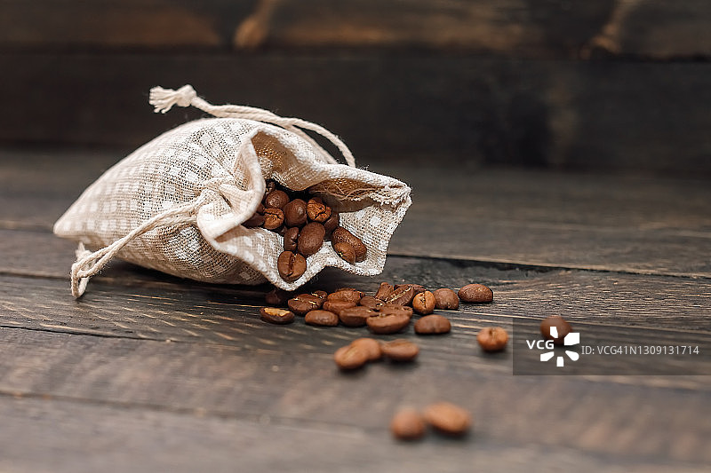 咖啡豆从袋子中散落在木质背景上图片素材