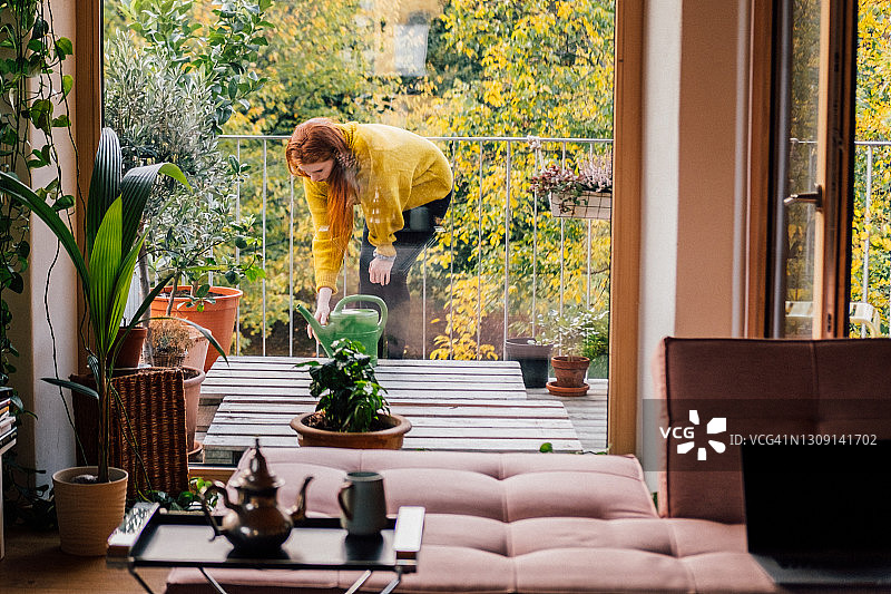 在阳台上照料植物的年轻女人图片素材
