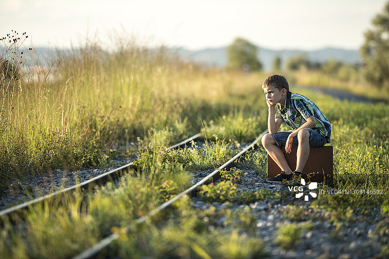 男孩背着包在铁轨上保持平衡图片素材