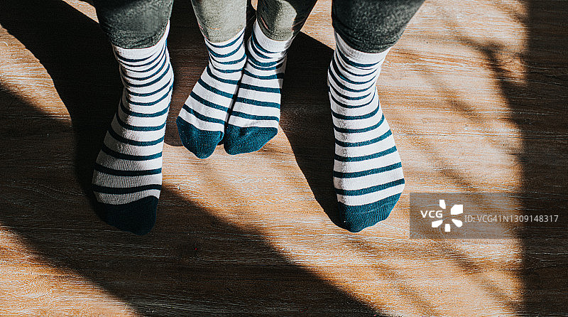 穿着相同条纹袜子的较大脚之间的小脚图片素材