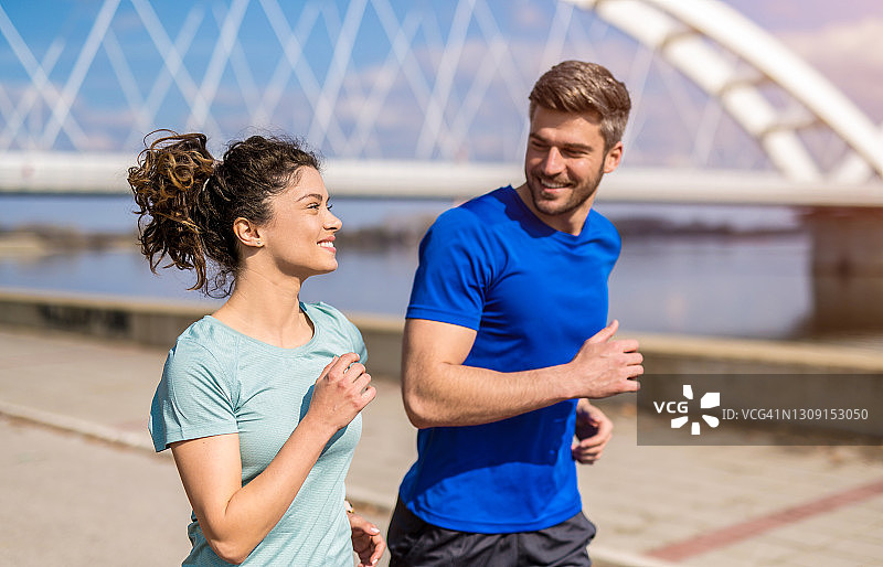 年轻情侣在户外河边奔跑图片素材