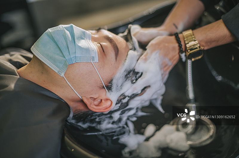 中国男子在理发店享受洗发服务图片素材