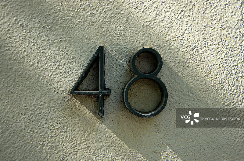 奶油色粉刷灰泥墙上的凸起金属数字48图片素材
