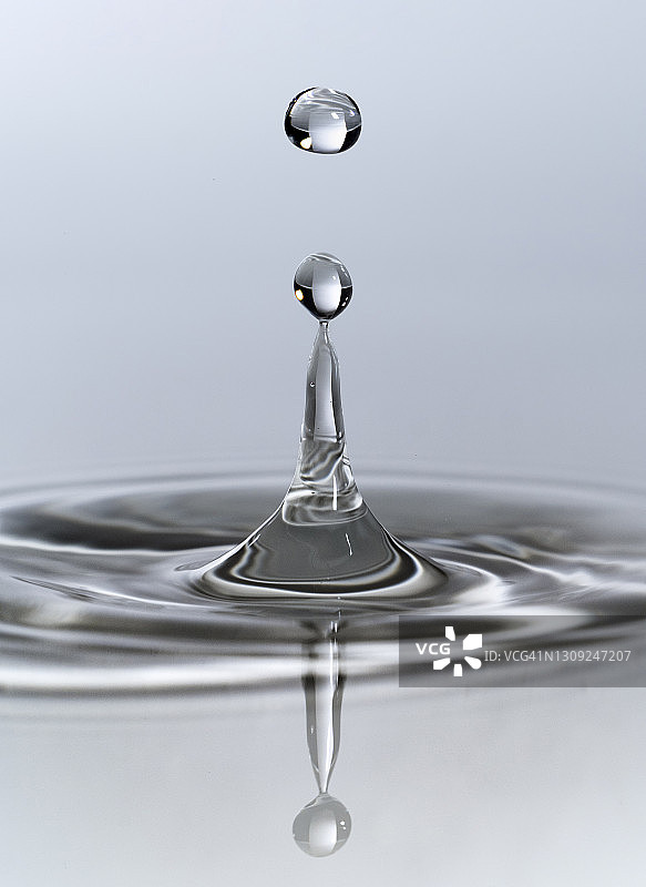 水滴撞击白色背景下的液体表面图片素材