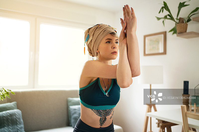 在家练习鹰式瑜伽的年轻女人特写图片素材