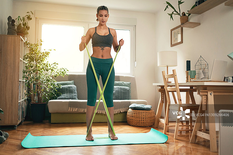 年轻女人在家使用阻力带锻炼图片素材
