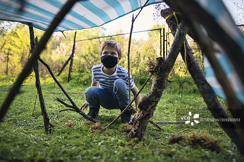 小男孩在秋季森林里搭建树枝庇护所图片素材