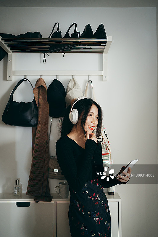 在家中用智能手机欣赏音乐的亚洲年轻女人图片素材