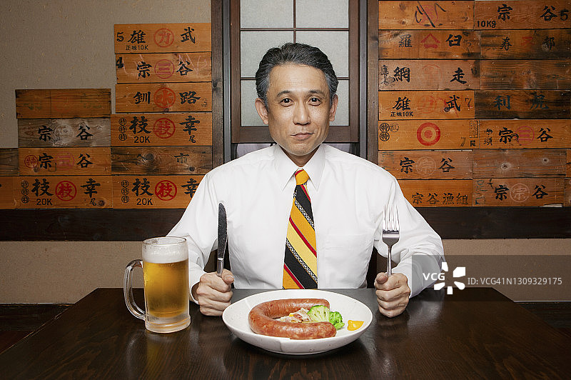 饥饿的商人手拿香肠和啤酒图片素材