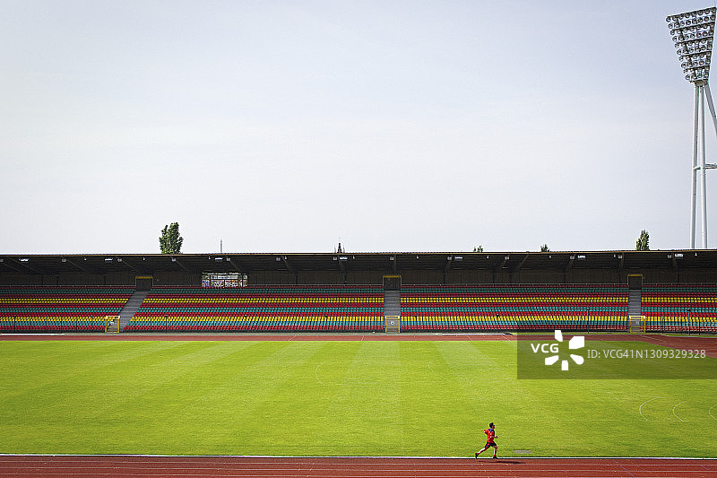 阳光明媚的足球场上的跑步男子图片素材