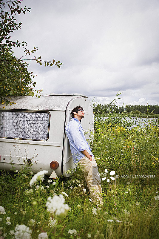 田园湖畔草地上的露营车旁的年轻人图片素材