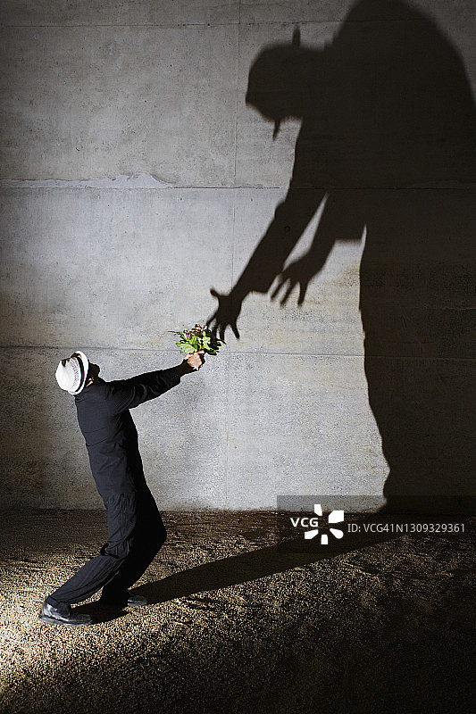 男人向墙上高大的不祥阴影献花图片素材