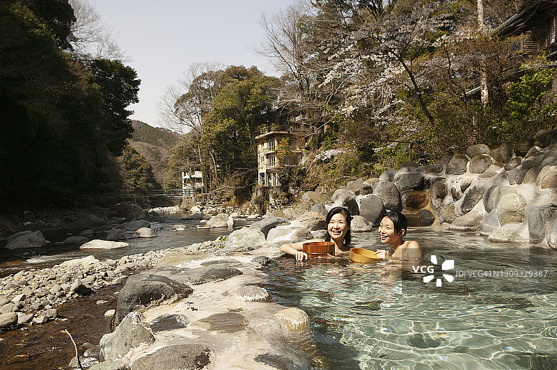 在日本伊豆的温泉池中享受阳光的快乐年轻女性图片素材