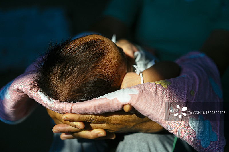 祖母抱着1个月大的宝宝在家晒太阳治疗黄疸图片素材