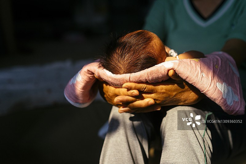 祖母抱着1个月大的宝宝在家晒太阳治疗黄疸图片素材