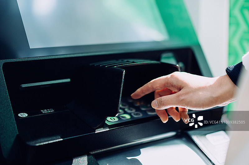 年轻女子在自动取款机上输入密码图片素材