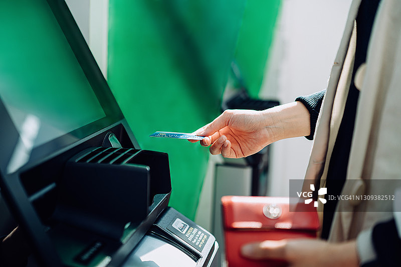 年轻女子在自动取款机上使用银行卡特写图片素材