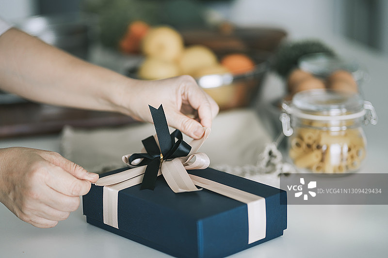 中国中年妇女在厨房柜台上接收并打开礼物图片素材