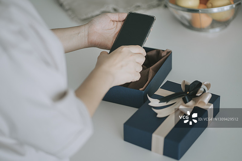 中国中年妇女在厨房柜台上接收并打开礼物图片素材