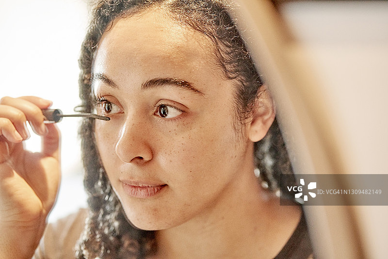 年轻女子在镜子前涂睫毛膏图片素材