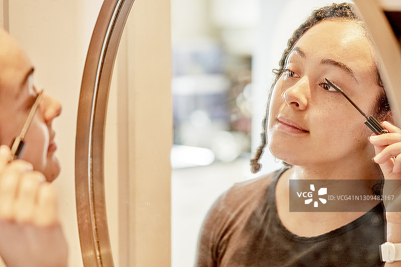 年轻女子在镜子前涂睫毛膏图片素材
