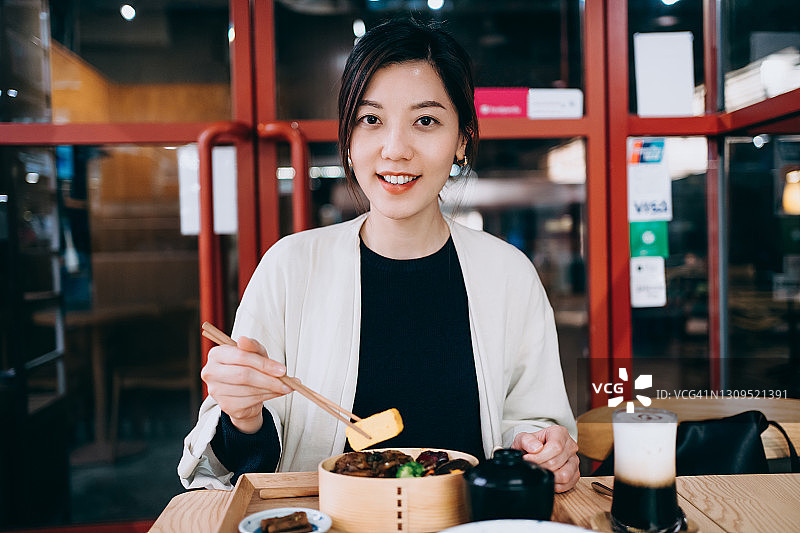 亚洲年轻女子在餐厅享用日式烤猪肉套餐图片素材