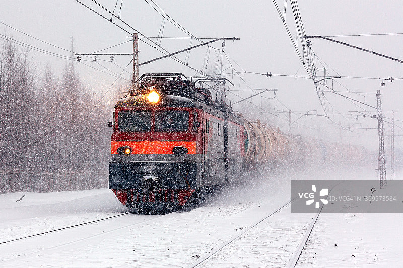 强大的电力机车与沉重的货运列车在大雪中图片素材