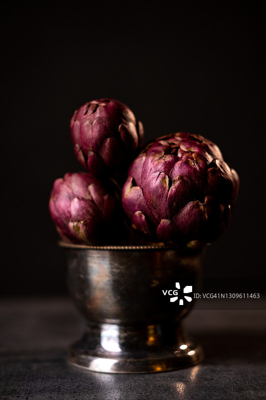 黑色桌子上碗里新鲜成熟的朝鲜蓟图片素材