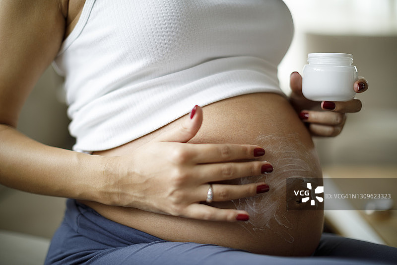 孕妇在腹部涂抹护肤霜，预防妊娠纹图片素材