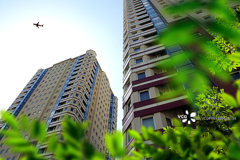 仰视居民楼和飞行中的飞机图片素材