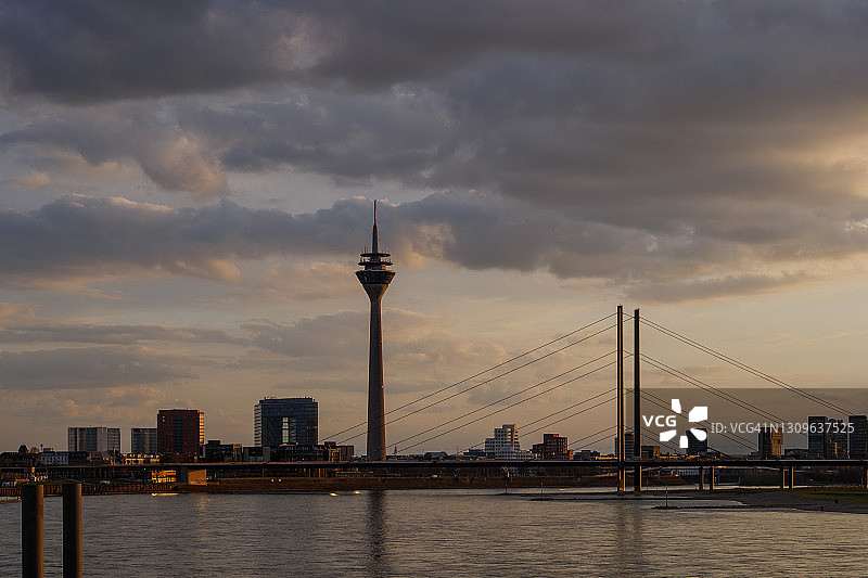 德国杜塞尔多夫城市天际线户外风光：莱茵塔、悬索桥和莱茵河在金色日落天空下图片素材