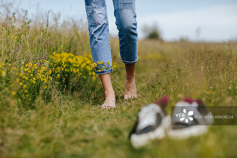 赤脚年轻女子在田园诗般的乡村野花田中图片素材