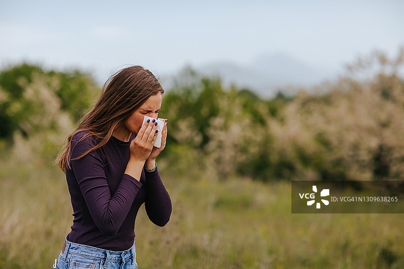 在户外因过敏症状而擤鼻子的女人图片素材