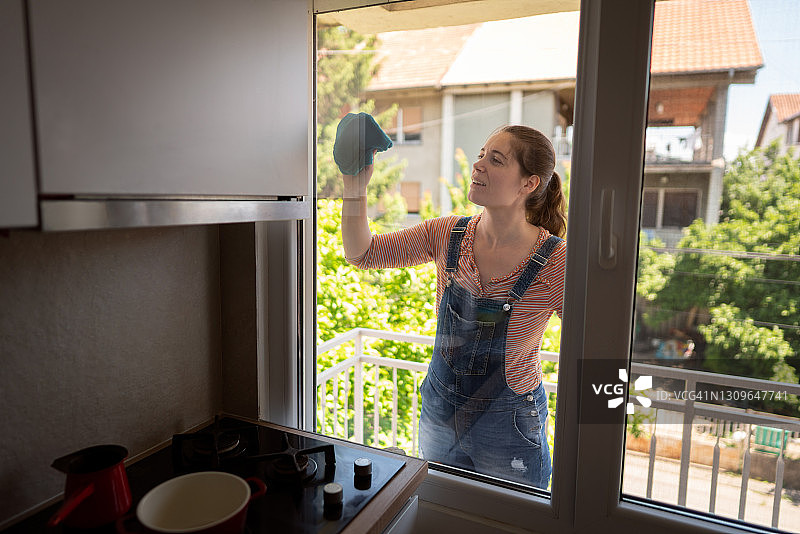 开心的女人在家清洁窗户图片素材