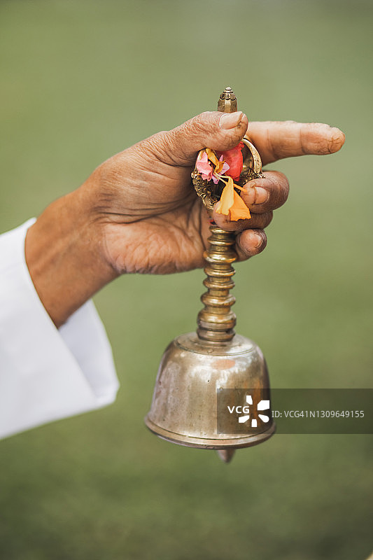在巴厘岛传统祭祀仪式上手持金属铃铛的男人图片素材