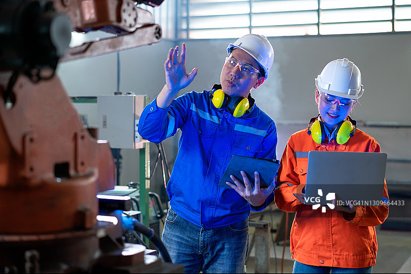 工程师和技术员使用平板电脑在机器人工厂工作，工业概念图片素材