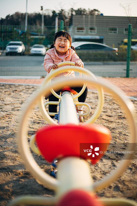 快乐的小女孩在游乐场玩跷跷板图片素材