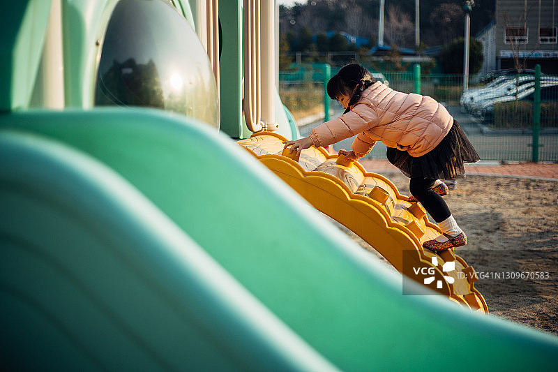 快乐的小女孩在游乐场的墙上攀爬图片素材